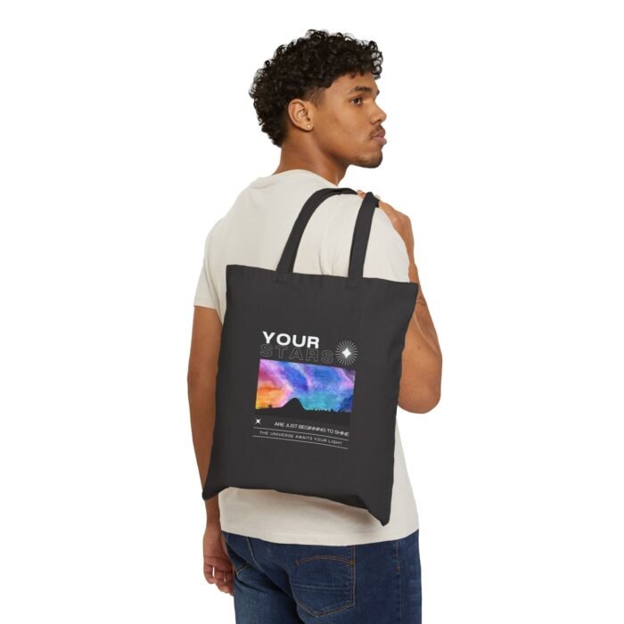 Man carrying a black tote bag with a cosmic sky and graduation-inspired design, ideal for everyday eco-friendly use.