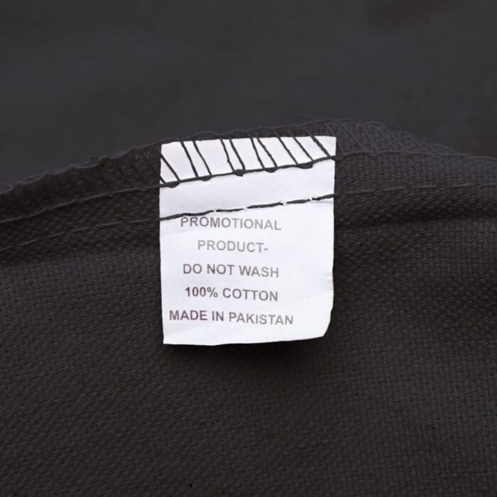Close-up of care label on the Graduation – Cosmic Sky tote bag, showing material and washing instructions.
