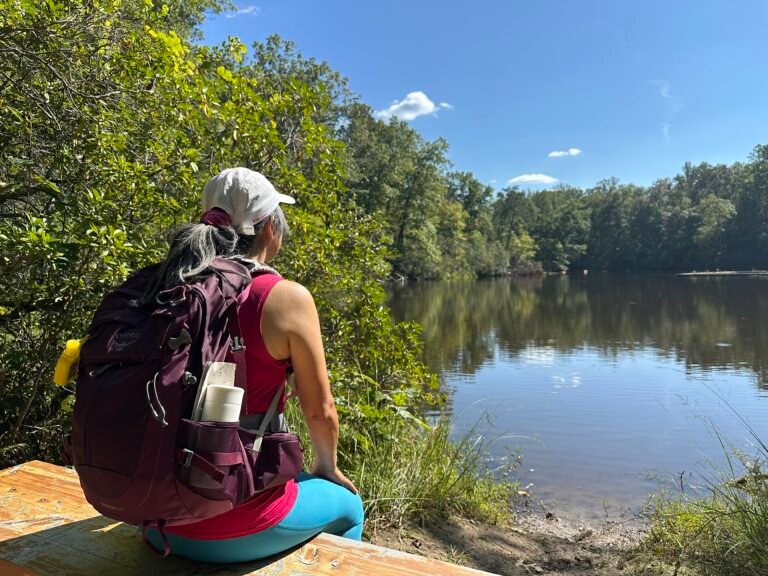 a hiking sitting on a bench watching the lake