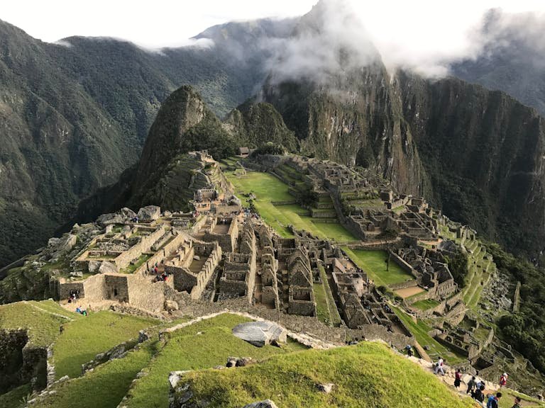 Stunning aerial view of Machu Picchu with lush mountains and clouds in the background.