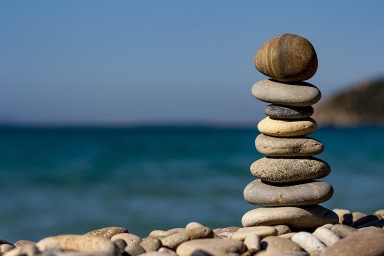 A stack of balanced stones on a beach with a tranquil ocean backdrop for meditation and zen.